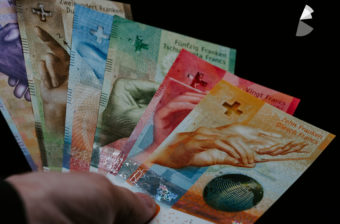 Photo showing Swiss bank notes fanned out in a hand.