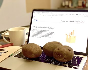 An open laptop with 3 potatoes on the keyboard and Google Analytics displayed on the screen.