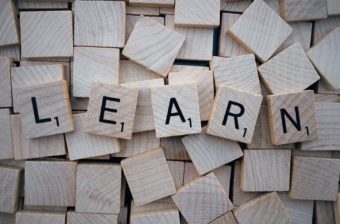 Image of wooden scrabble tiles. All the tiles are face down apart from five which spell out the word 'Learn'